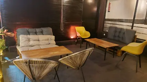 Sofás con cojines y sillas amarillas en la terraza, de noche