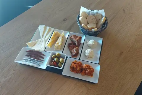 Tabla con tortilla, quesos, embutido, anchoas y olivas en una mesa de madera